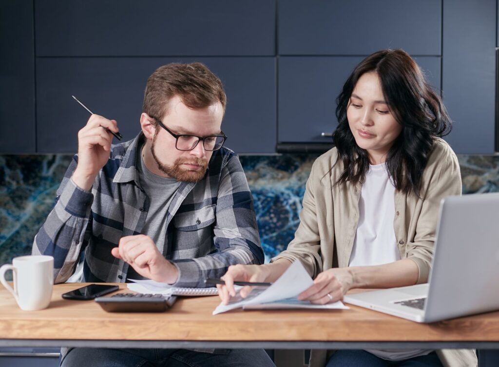 Een stel bespreekt het huishoudbudget met een rekenmachine — sfeerbeeld